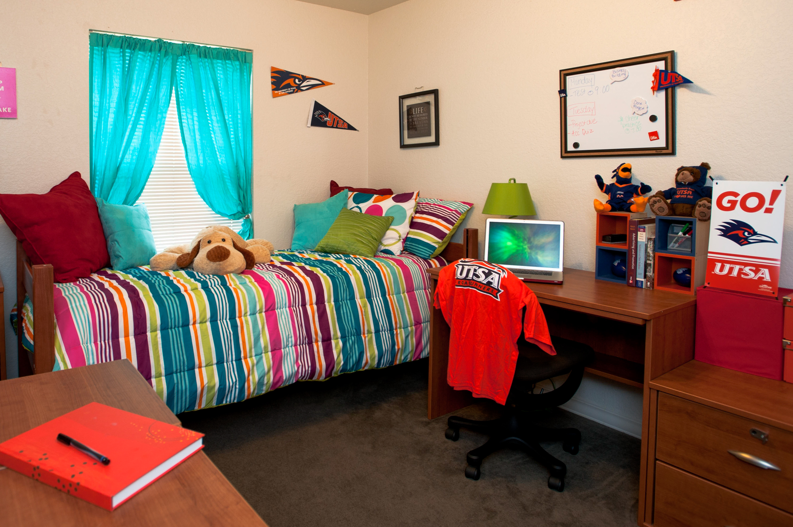 A picture of a UTSA dorm room of a bed and desk with a window